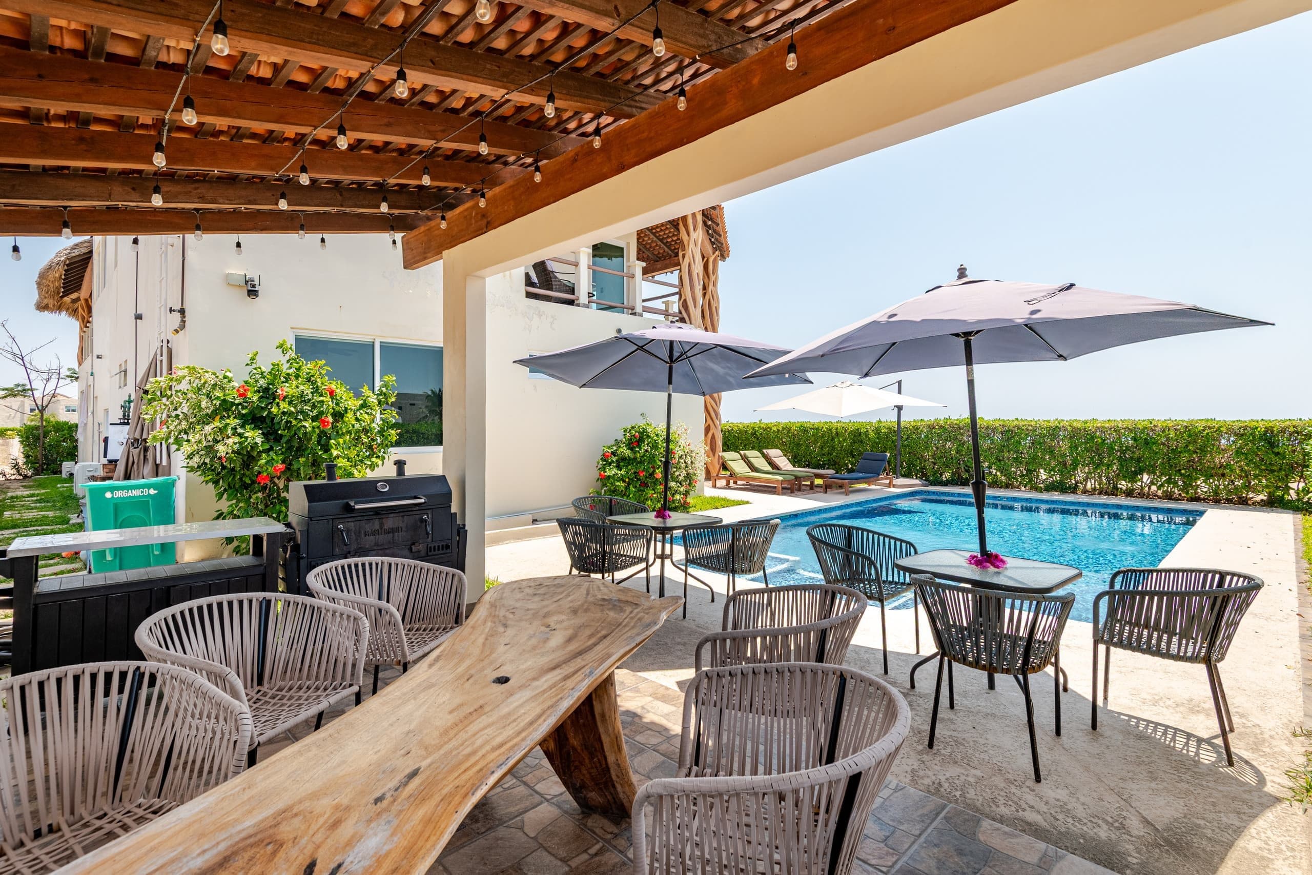 Terraza con mesa de madera y sillas junto a la alberca