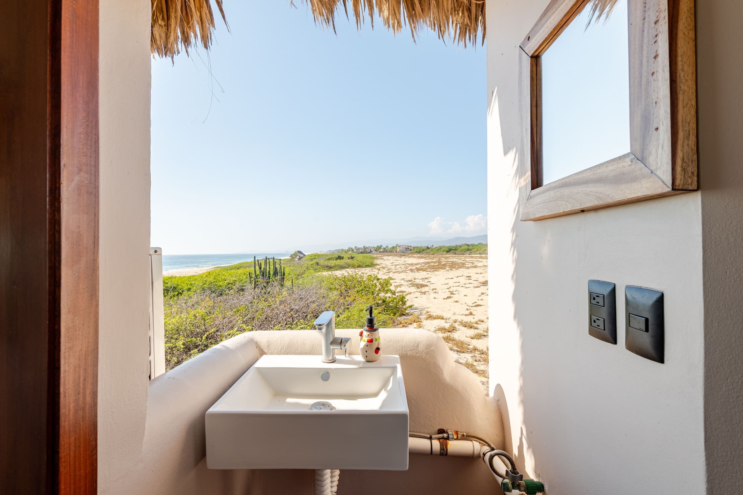 Baño con lavabo frente a una ventana con vista a la playa