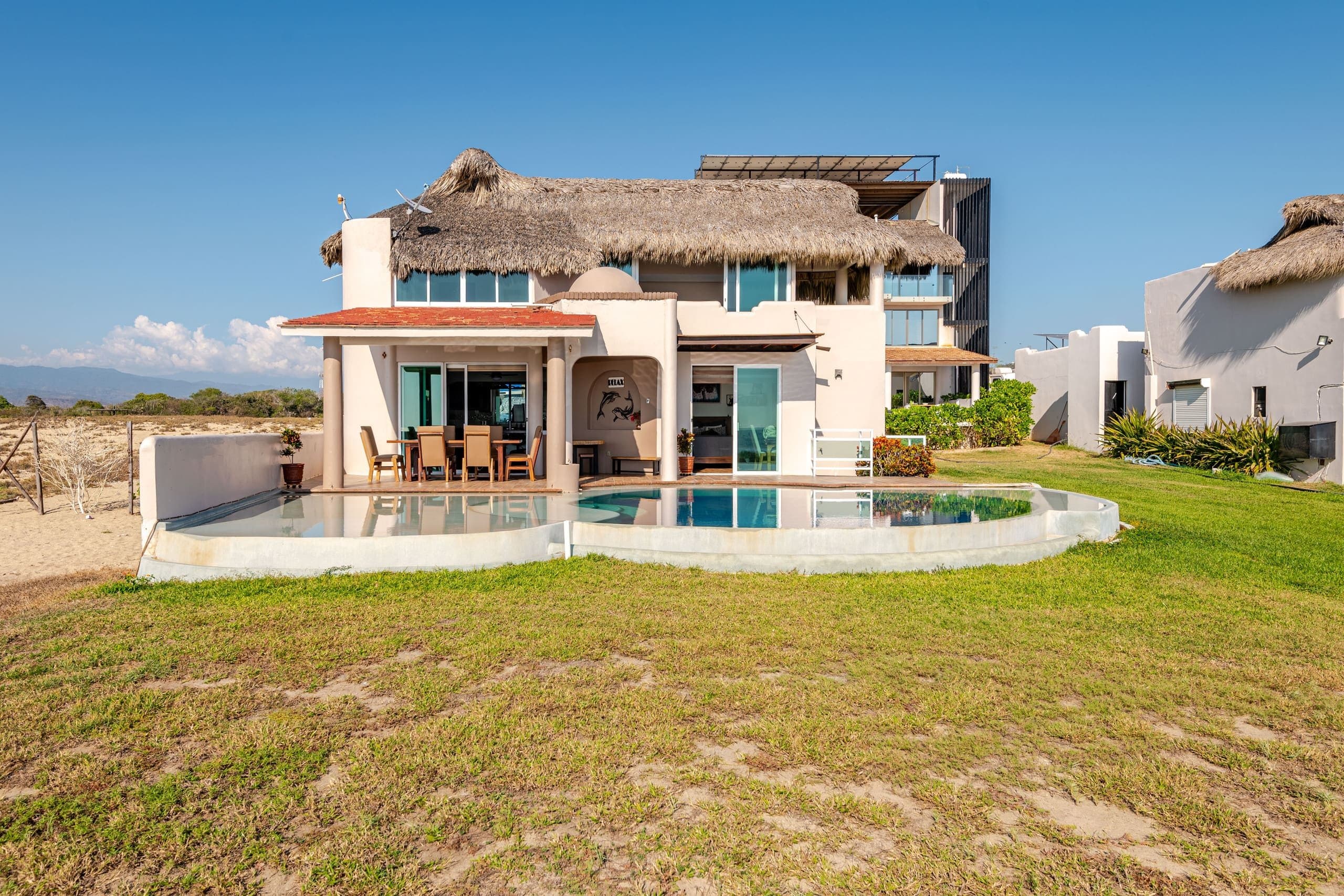 Casa Delfines con techo de palapa y alberca frente al jardín