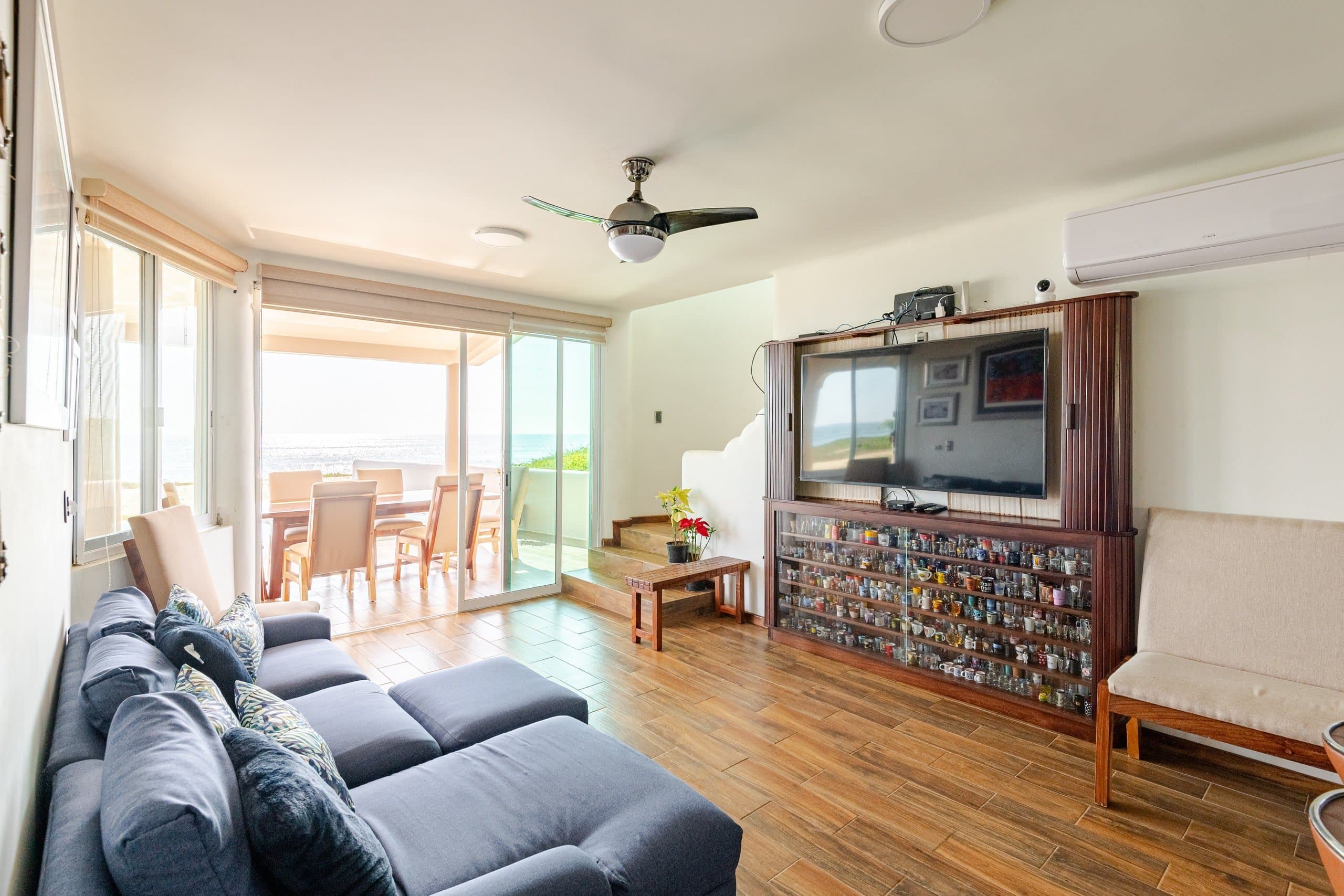 Sala con sofá azul y ventanales hacia el mar