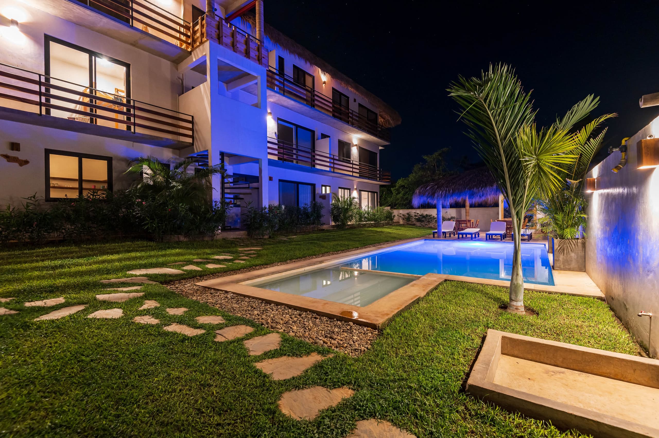 Alberca y jardín del condominio iluminados de noche