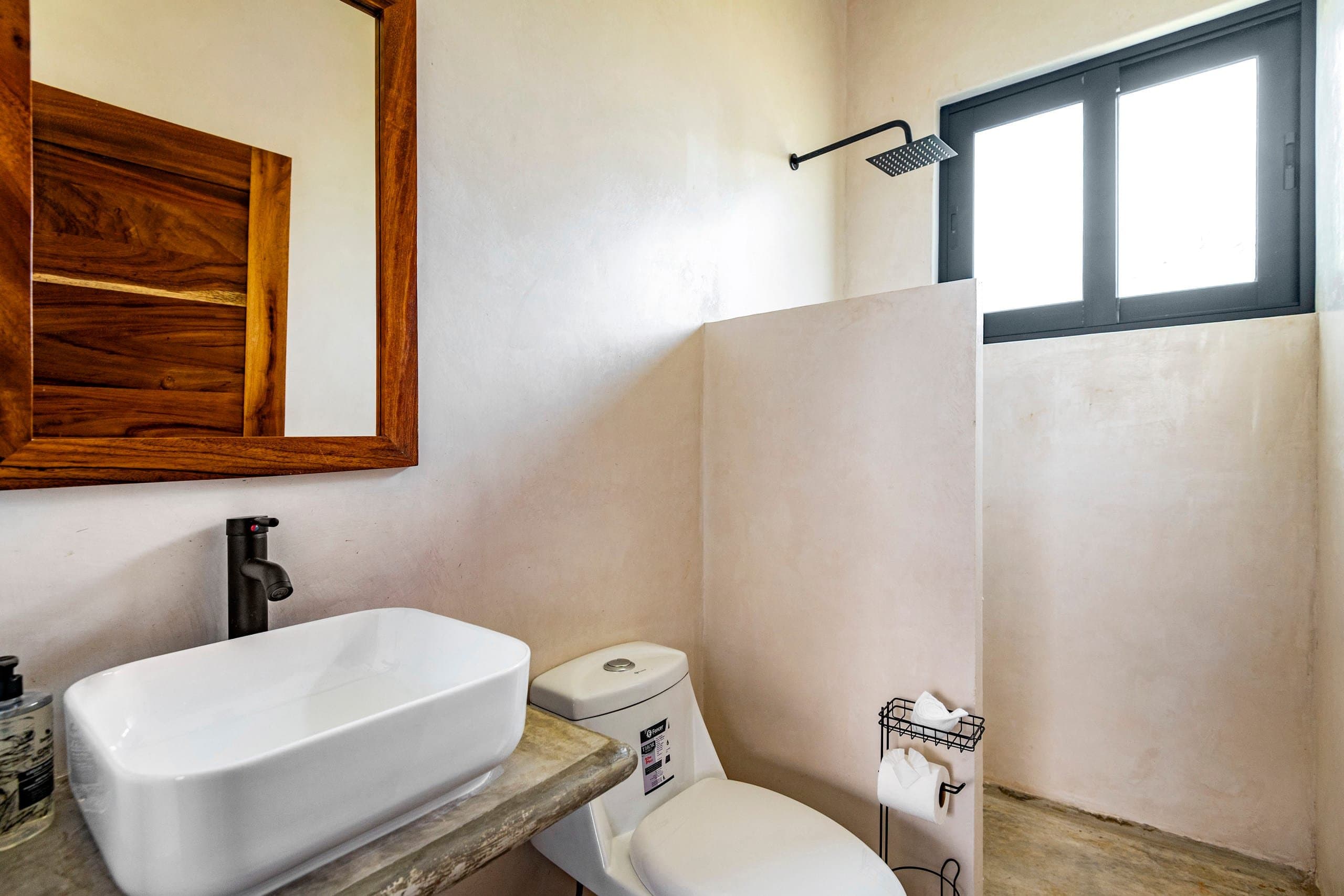 Baño con lavabo blanco y espejo de madera