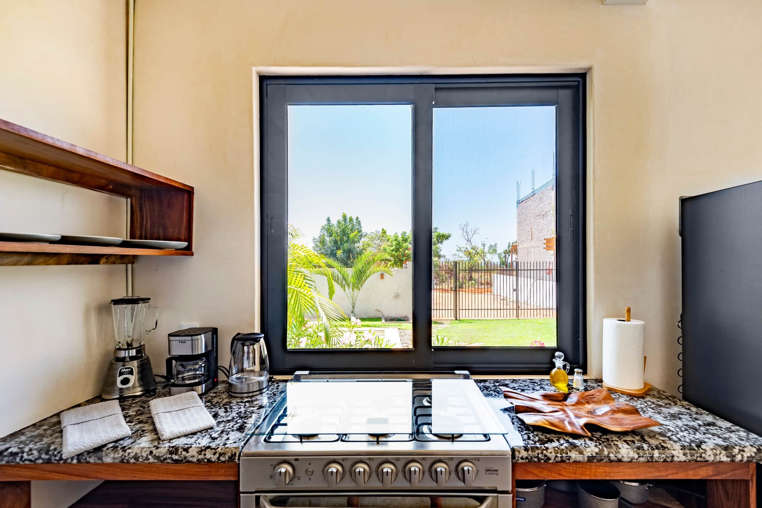 Cocina con barra de granito y ventana al jardín
